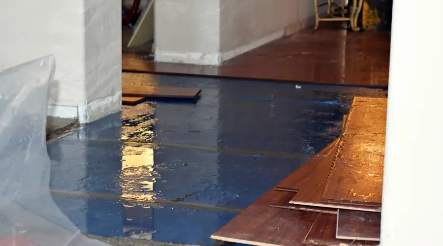 how-long-does-it-take-to-dry-out-a-flooded-basement-in-maryland - First & Last Restoration Under renovation: blue epoxy floor coating with scattered wooden floor planks and construction debris nearby.